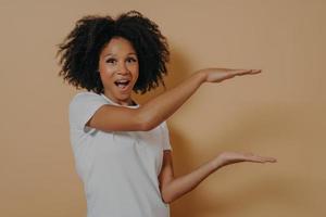 Salió afroamericana hermosa mujer joven con cabello rizado negro mostrando con manos ejemplo de tamaño foto