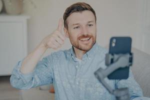 Young man showing thumbs up gesture while video chatting on phone photo