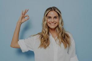 Happy smiling blonde woman showing ok gesture photo