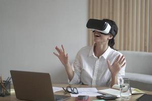 Business lady wears VR headset for laptop raising hands up as trying to touch objects in 3D reality photo
