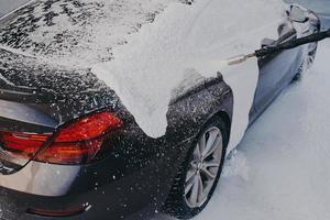 Car in white soap suds during professional auto cleaning outdoor photo