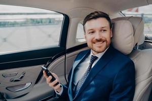 Corporate executive in elegant expensive tuxedo rides in luxury car photo