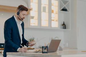 Executive director reading document and writing notes in notepad while working at home photo