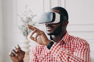 Young african businessman wearing VR glasses touching 3d objects, interacting with virtual reality photo