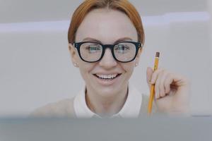mujer joven estudiando con cámara. estudiante feliz sosteniendo un lápiz y tomando notas. la educación a distancia.