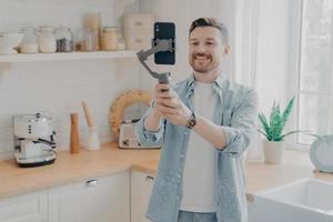 Young man blogger recording video blog with mobile phone at home photo