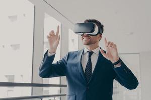 Excited office worker in vr headset or virtual reality goggles gesturing with hands photo