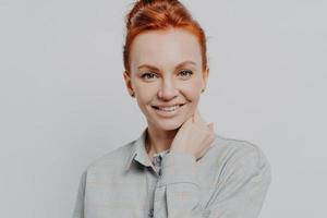 Happy redhead woman looking at camera white toothy smile isolated over grey background photo