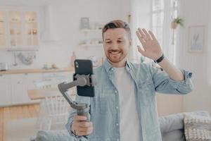 Photo of handsome guy in living room making selfie on smartphone