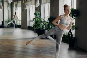 Athletic slender red haired woman during her fitness workout with rubber resistance band photo