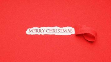 saludo de feliz navidad visto a través del agujero en el fondo de papel rojo foto