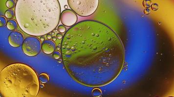 abstracte kleurrijke voedselolie druppels bubbels en bollen stromen op het wateroppervlak, macro videografie video