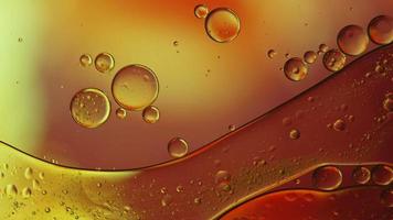 olio di cibo colorato astratto gocce bolle e sfere che scorrono sulla superficie dell'acqua, videografia macro
