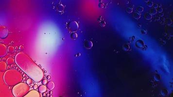 el aceite alimentario colorido abstracto cae burbujas y esferas que fluyen en la superficie del agua, videografía macro video