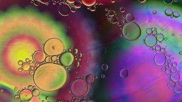 abstracte kleurrijke voedselolie druppels bubbels en bollen stromen op het wateroppervlak, macro videografie