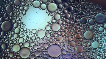 óleo de comida colorido abstrato deixa cair bolhas e esferas fluindo na superfície da água, macro videografia video