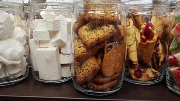 Cookies and marshmallows with nuts in glass jars on the store shelf video