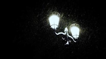 farola brillante brillando a través de fuertes nevadas en la noche. farola en medio de la ventisca, en kyiv, ucrania. Vídeo de alto contraste de 4k.