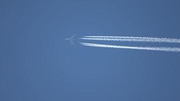 Jet airliner flying high in the sky leaving contrails in the clear blue sky. video