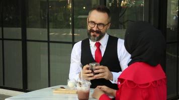 retrato de una joven alegre hablando con un amigo o colega durante una reunión de negocios en la terraza de un café al aire libre video