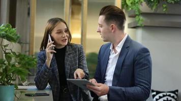 dois jovens colegas conversando juntos em um intervalo. grupo de empresários de inicialização trabalhando todos os dias no escritório moderno. video