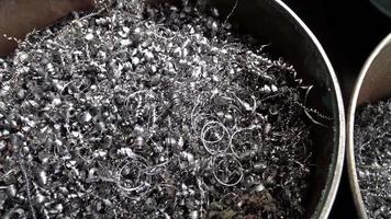 Steel scrap materials recycling. Aluminum chip waste after machining metal parts on a cnc lathe. Closeup twisted spiral steel shavings. Small roughness sharpness, possible granularity, blurred focus video