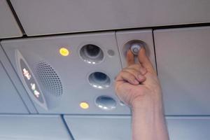 Hand man up to adjust console panel. The air condition, light, low cost airline seat. While on board of an aircraft, selective focus. Blur background color vintage style. photo