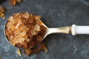 Rock sugar in a spoon on a black background. photo