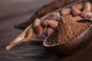 granos de cacao en la fruta seca de la vaina de cacao sobre fondo de madera foto