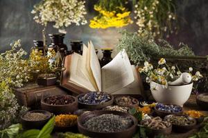 Herbal medicine and book on wooden table background photo