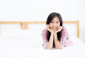 Beautiful portrait young asian woman lying and smile while wake up with sunrise at good morning, girl with happy, lifestyle and relax concept. photo