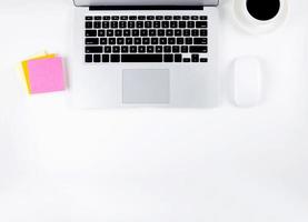 Top view of laptop computer and mouse, diary and notepad for reminder and a cup of coffee isolated on white background, notebook and supplies on desk office, business and workplace concept. photo