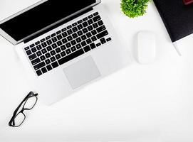 Top view of laptop computer with open display screen monitor, mouse and notepad and glasses isolated on white background, notebook or netbook with keyboard, communication technology concept. photo