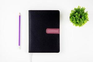 Black cover leather notebook or diary for reminder and memo and planner isolated on white background, book mockup and pencil and tree, education and supplies concept. photo