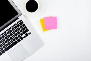 Top view laptop with open display screen monitor, diary and notepad for reminder and a cup of coffee isolated on white background, notebook and supplies on desk office, business and workplace concept. photo