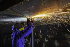 Male worker  grinding on steel plate with flash of sparks close up wear protective gloves