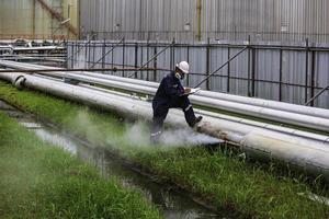 Trabajador de sexo masculino inspección visual de la tubería de petróleo y gas corrosión óxido a través del tubo del zócalo tubería de fuga de gas de vapor foto