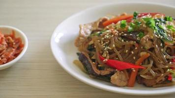 Japchae ou macarrão aletria coreano frito com legumes e carne de porco coberto com gergelim branco - estilo de comida tradicional coreana video