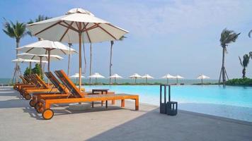 umbrella with bed pool around swimming pool with ocean sea background - holiday and vacation concept video