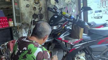 jayapura, indonésia, 17 de abril de 2022, os senhores estão consertando o freio dianteiro da moto satria f150 video
