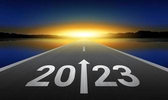 2023 New Year Background Design. Text 2023 written on the road in the middle of asphalt road at sunrise.