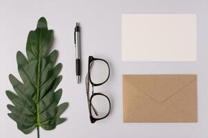 envenlope, card, pen, notebook, glasses, and leaf branchs on white background photo