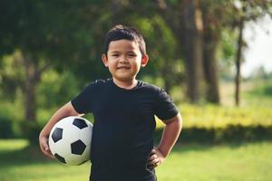 niño pequeño mano sujetando fútbol soccer foto