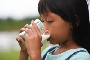 Little girl drinking milk in the park photo