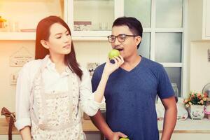 Happy couple Eating fresh apple.Having fun in the kitchen. photo