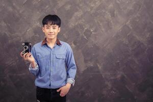 Handsome young man standing holding retro camera on grunge wall photo