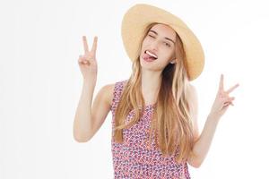 Beautiful woman with hat smiling on a background of white show victory signs and tongue. photo