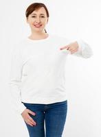 White long sleeve t-shirt on a middle aged woman in jeans and pointed hand isolated, front , mockup photo