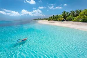 Caucasian couple of tourists snorkel in crystal turquoise water near Maldives Island. Perfect weather conditions at luxury resort beach scene, calm sea water, couple exotic water, underwater wildlife