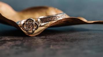 Closeup of a diamond engagement ring placed on a leaf. Love and wedding concept. photo